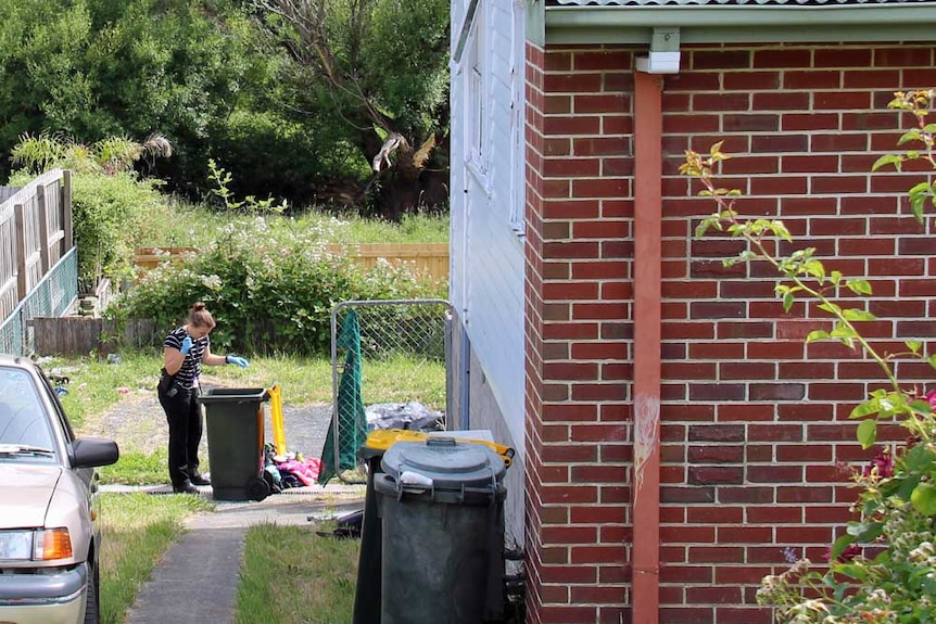 A Tasmanian police officer searches a bin
