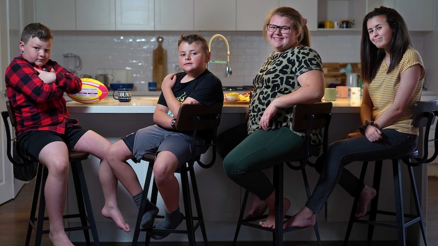 Four kids sit at a breakfast bar.