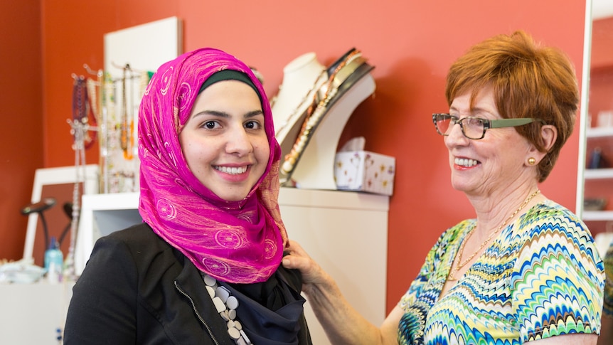 One woman rest her hand on the shoulder of another woman in an office