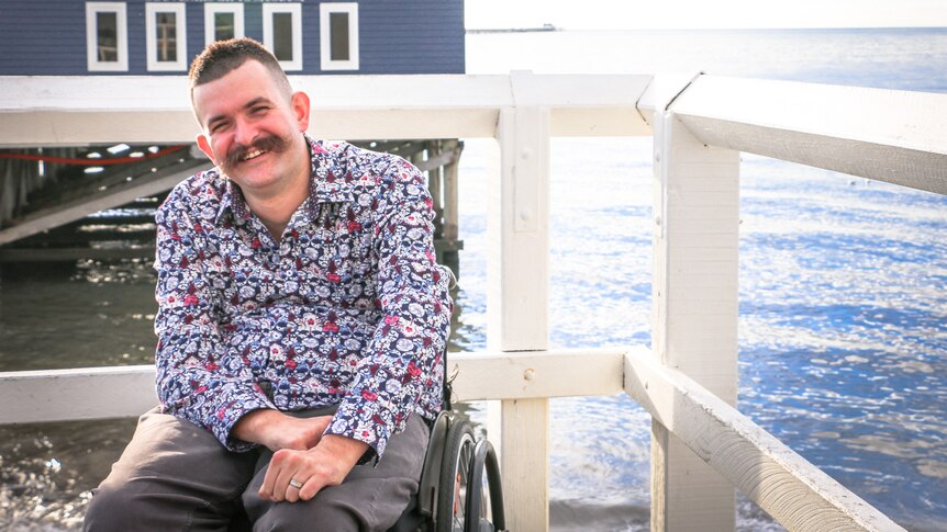 A man with a large moustache, in a wheelchair, on a jetty