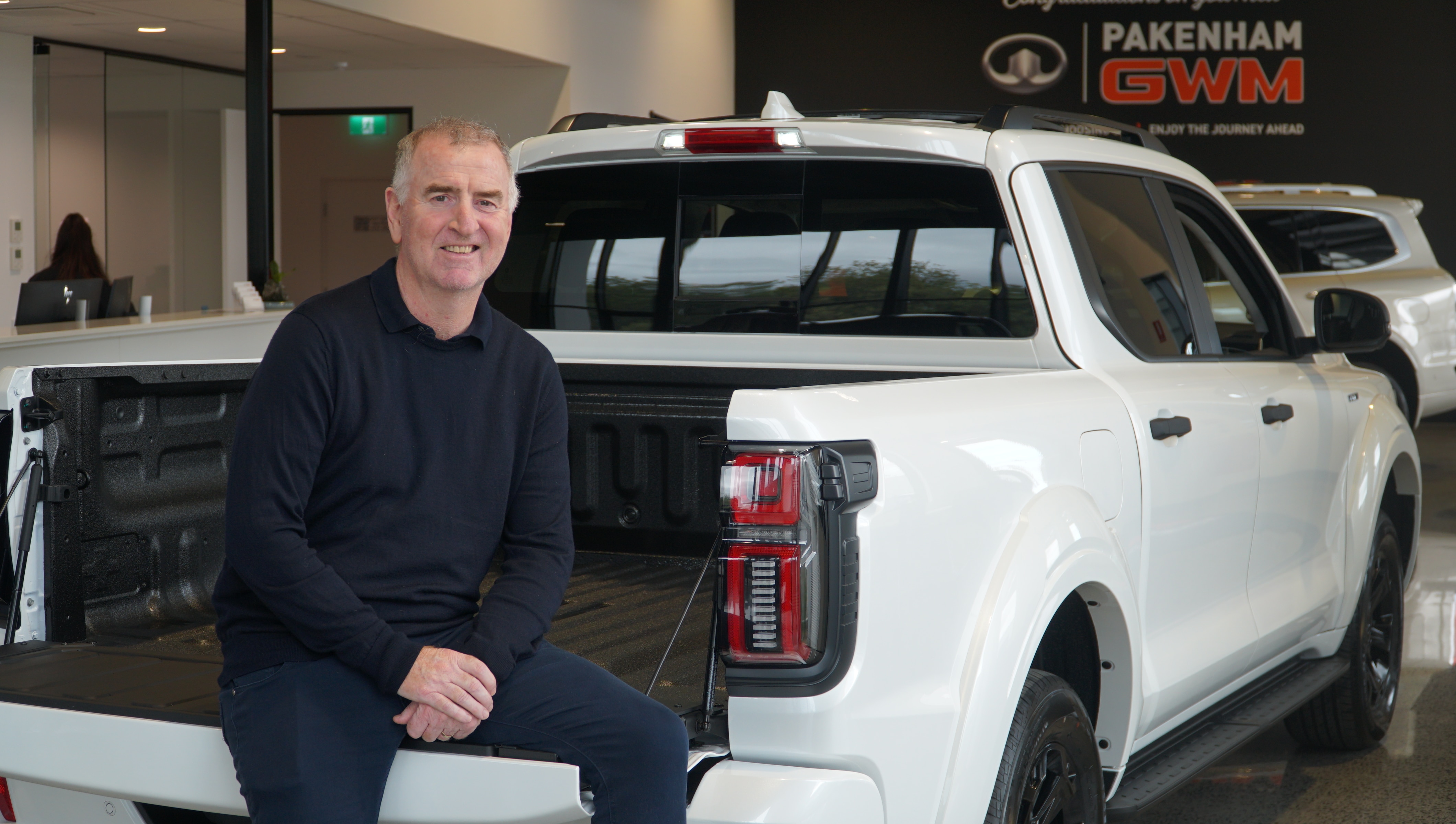 一名男子坐在一辆白色电动皮卡上。