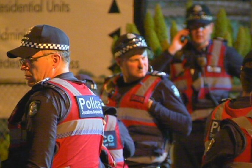 A close-up of three police officers at a youth justice centre at night.