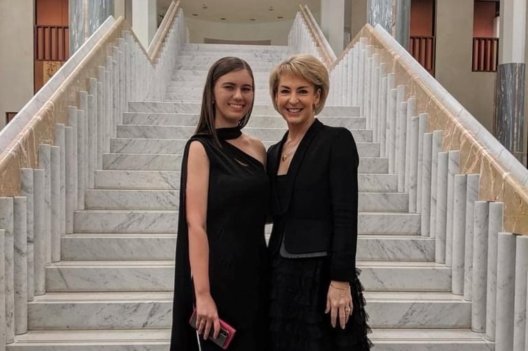 Two women smile in ball gowns