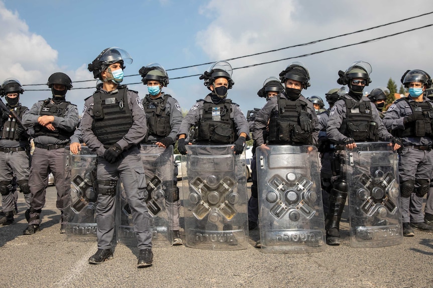 Armoured Israeli riot policemen stand in position for a protest