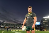 Michael Hooper wearing a green Wallabies jersey stands against a dark sky.