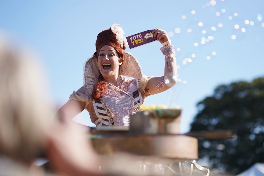 A drag queen smiles and holds a 'vote yes' sticker at the Come Together For Yes rally in Sydney