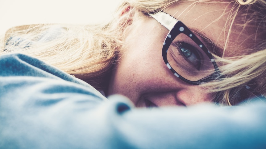 A woman in designer glasses smiles.