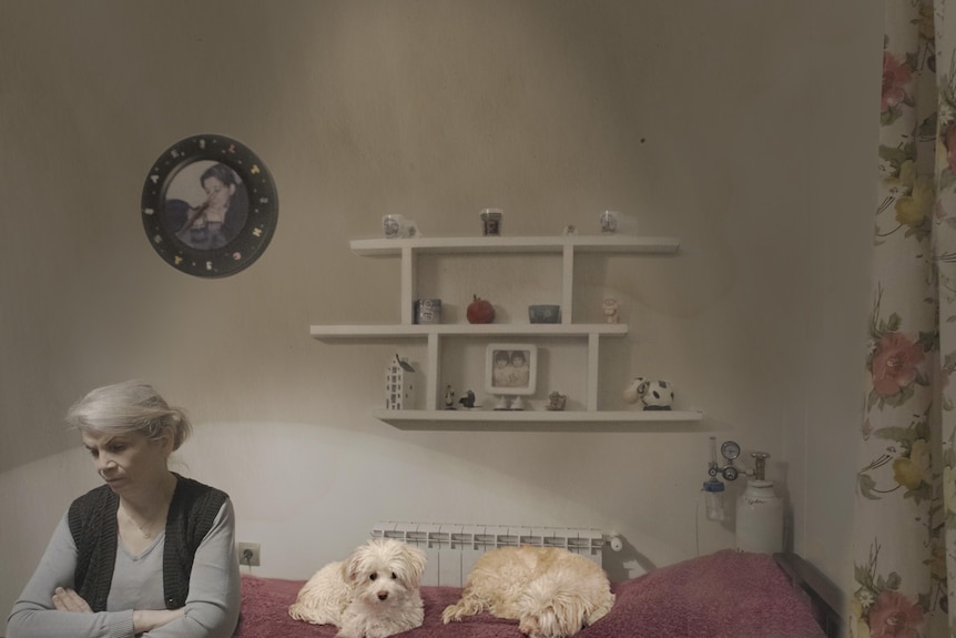 an older lady on a set of a movie with two dogs on the bed beside her