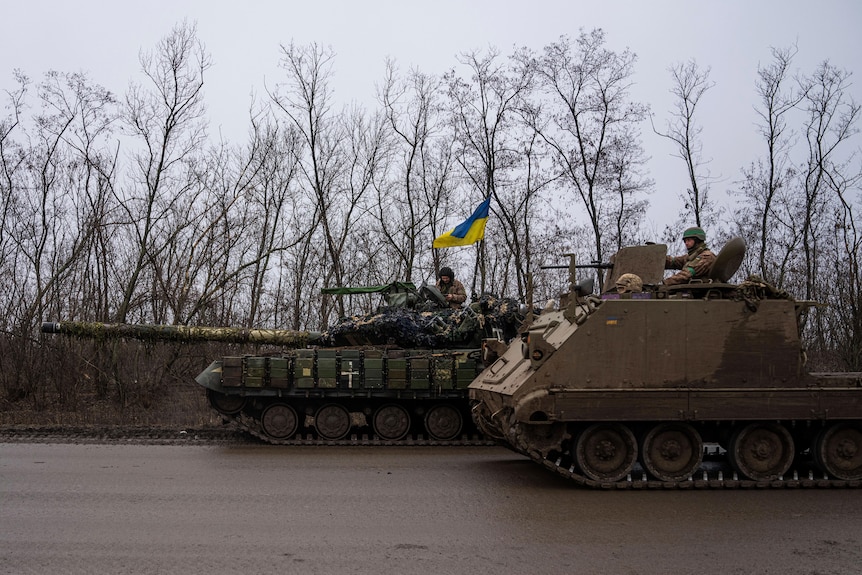 A Ukrainian serviceman in a tank prepares to shoot while his comrade passes by in an armoured vehicle.