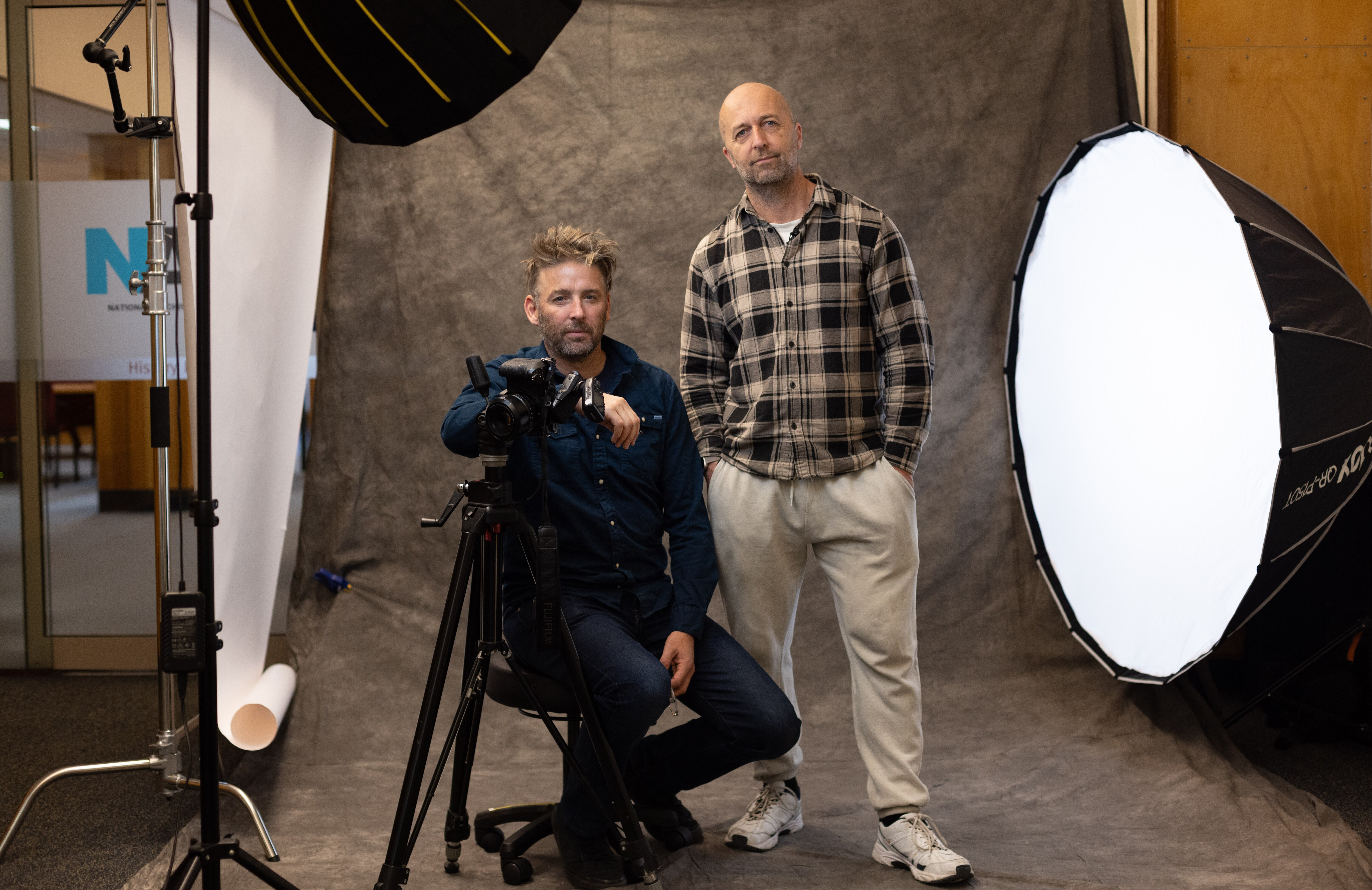 Two men posing for a photo in a set up photo studio.