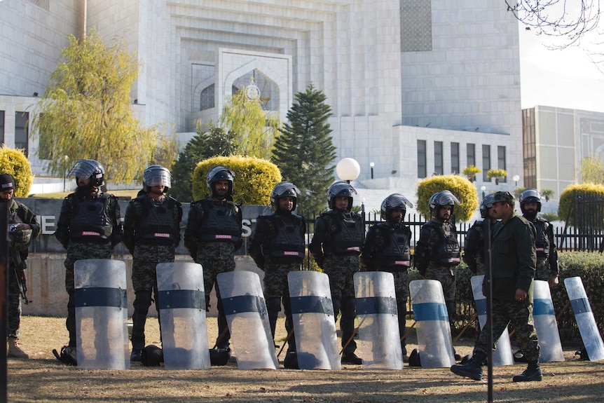Soldiers wearing riot gear with shields stand in a line outside the Supreme Court building.