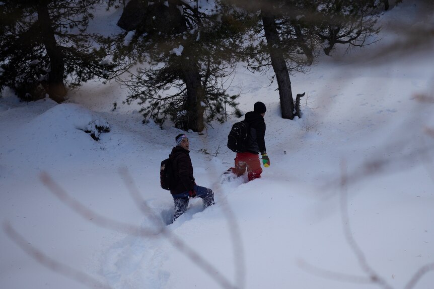 Two men trek through snowy conditions in the Alps.