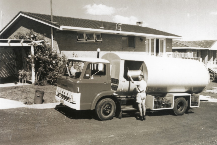 1960s photo of man loading bin into garbage truck