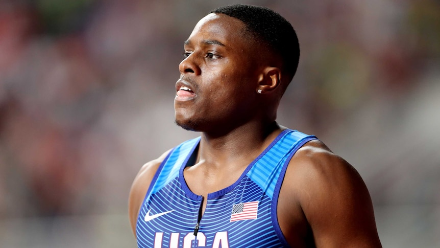 Christian Coleman looks to one side wearing a tight blue singlet with 'USA' written on the front