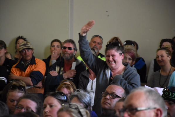 A woman unsure whether her home has been lost, before being reassured by another person at the meeting that it is "fine".