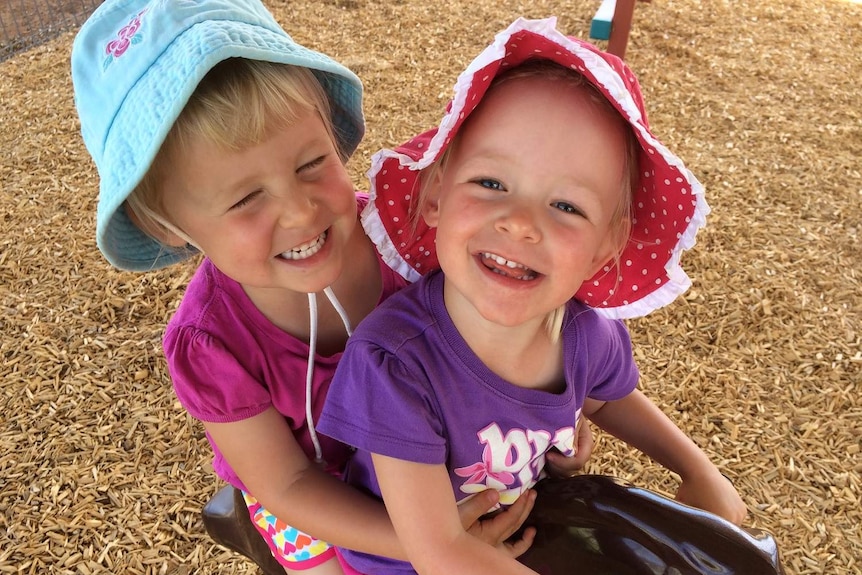 Monique Squires with her twin sister Zoe play on play equipment in the park.