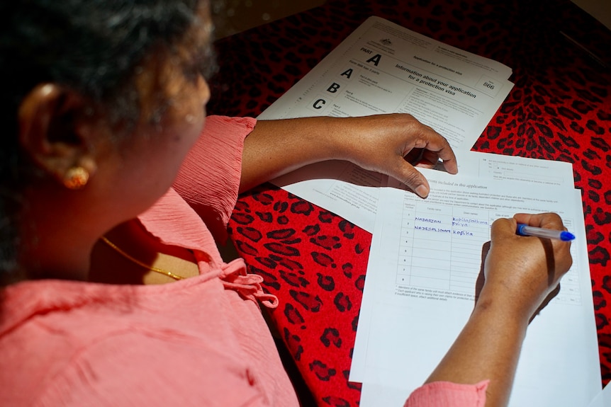 A view from above showing the back of a woman's head as she signs paperwork at a table