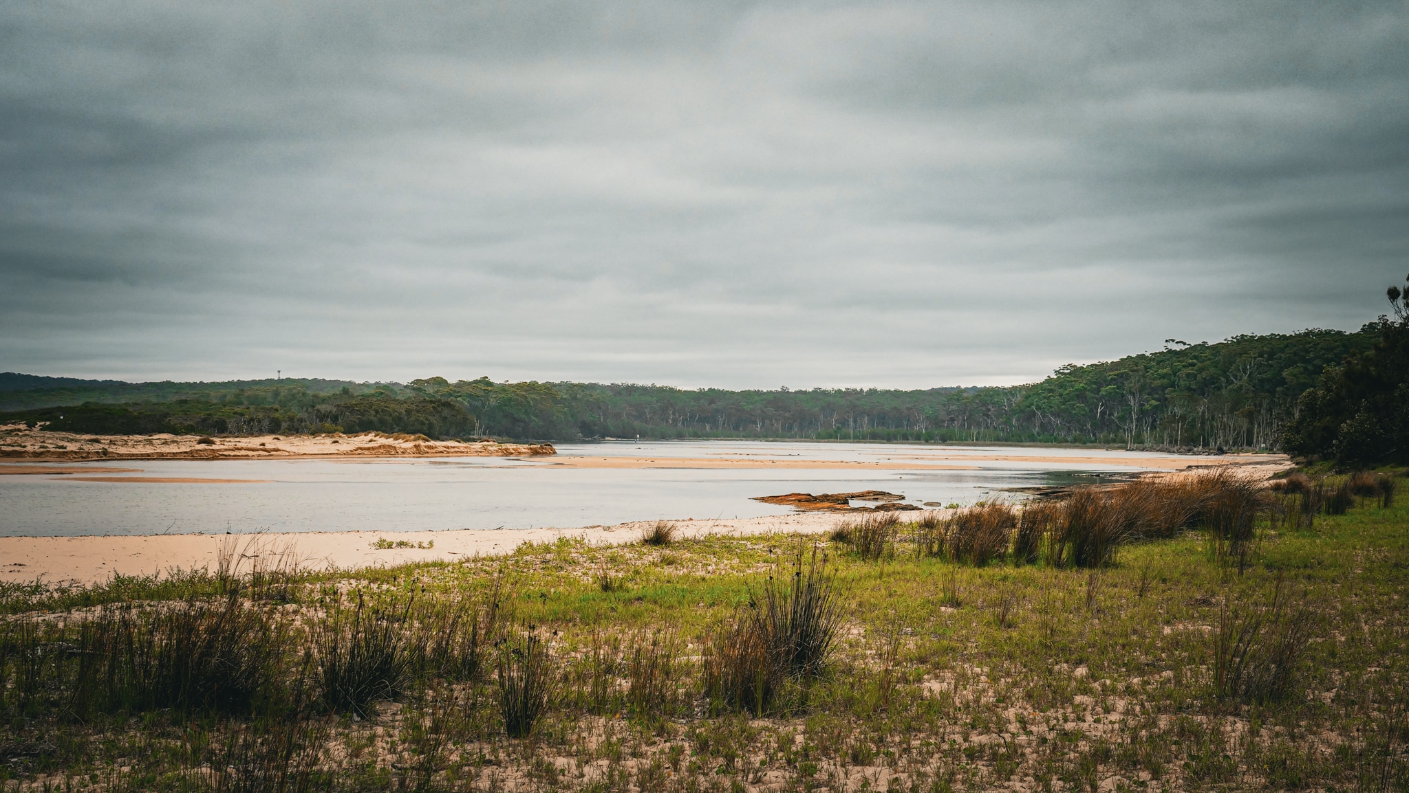 A calm inlet showing ocean, sand and bushland