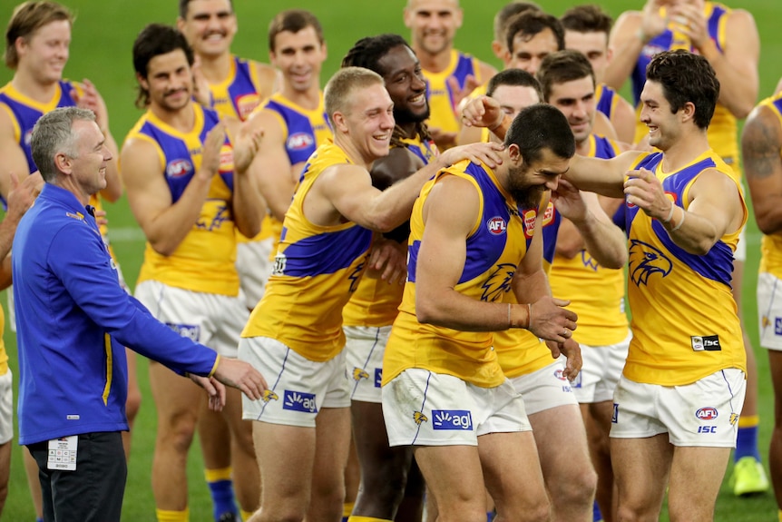 A West Coast Eagles player, is congratulated by teammates and coach following a win over the Fremantle Dockers