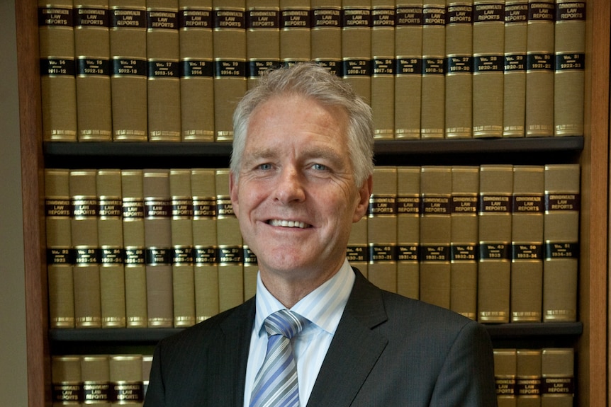 A photo of Justice Bernard Murphy standing in front of a bookcase.