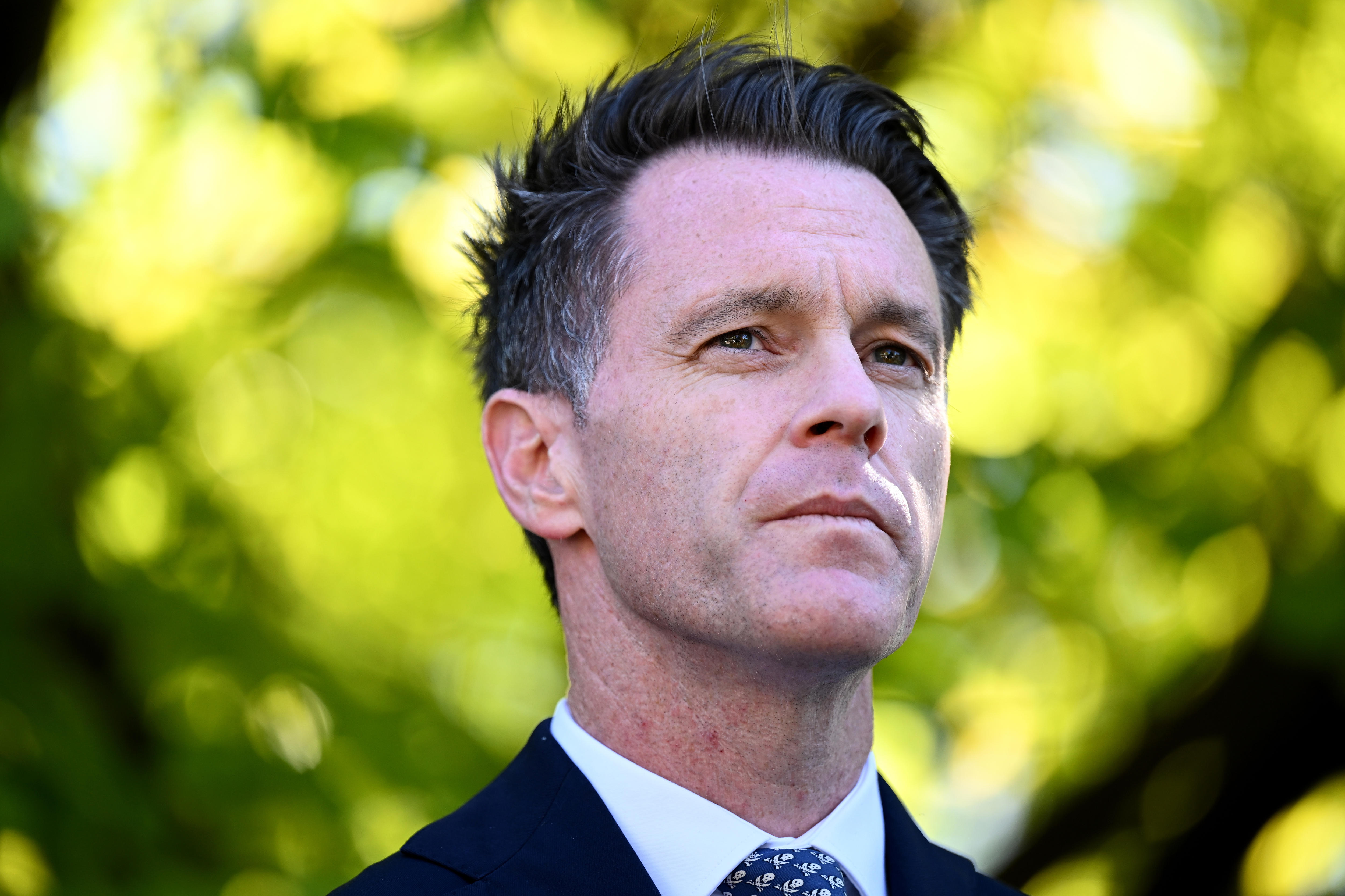 A portrait shot of a clean-shaven man with black hair, outdoors.