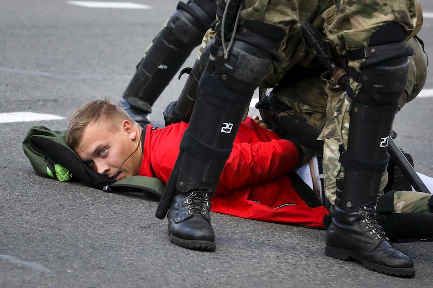A man on the ground with large police boots nearby.