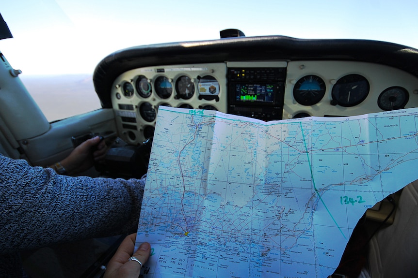 A person holding a map in a plane cockpit.