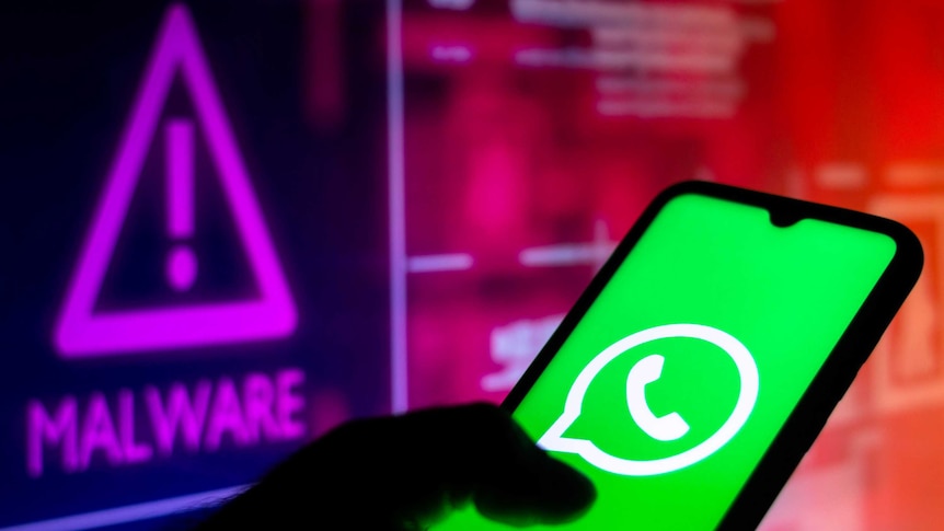 WhatsApp logo seen displayed on a smartphone with a malware alert in the background.