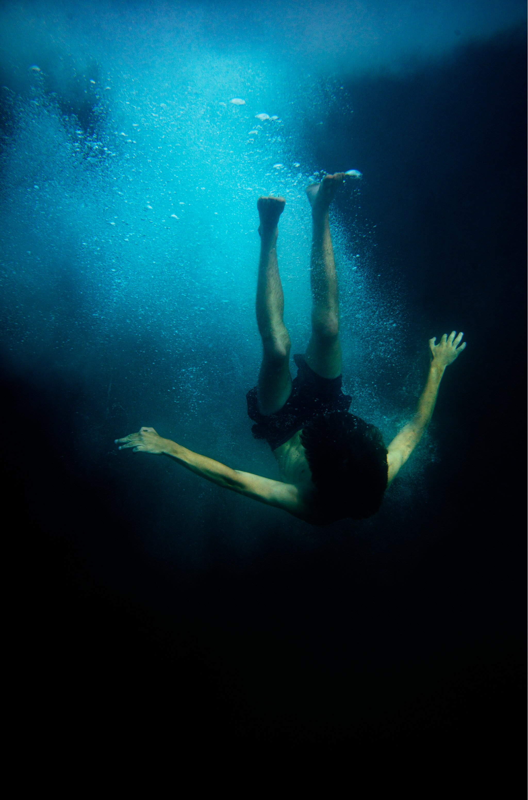 Underwater photo by Narelle Autio of a young male figure surging down into the ocean after jetty jumping