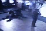 CCTV image shows three people on the floor and a person on a phone.