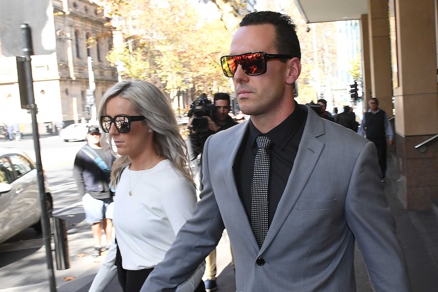 Andrew Lee (right) walks outside Melbourne Magistrates' Court holding hands with a woman.