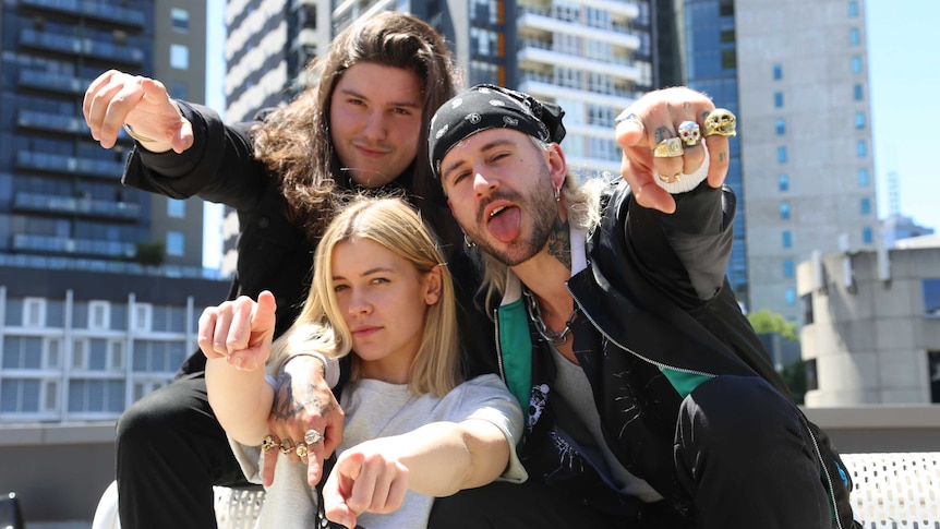 Sam and Twiggy from Ocean Grove with Bridget Hustwaite on a rooftop, pointing at the camera.