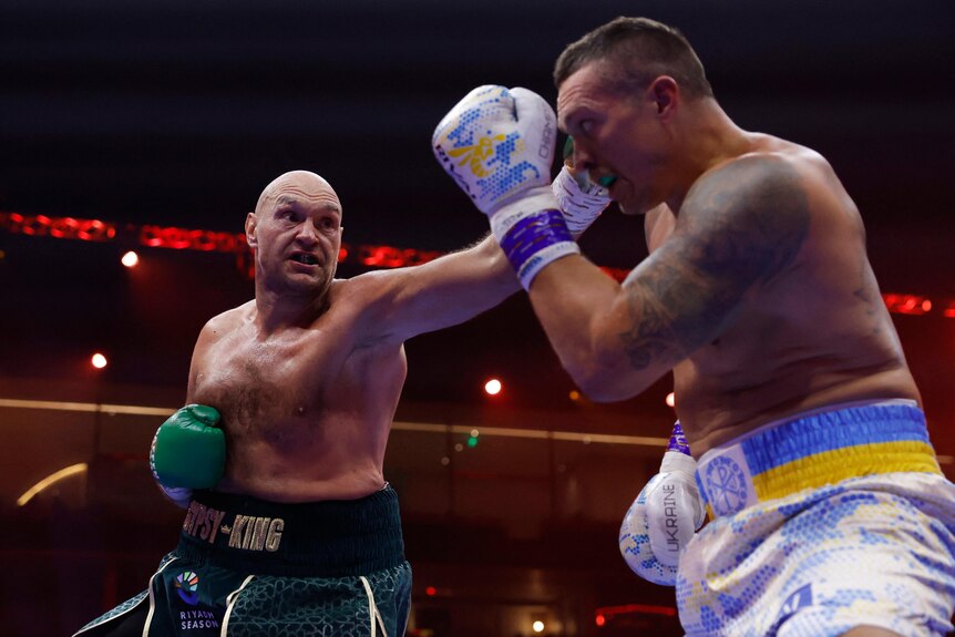 Heavyweight champions Tyson Fury and Oleksandr Usyk fighting in the ring, Fury throwing a punch, deflected by Usyk.