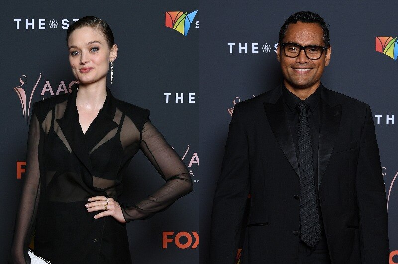 A woman in a sheer black dress poses on the red carpet, while a man in a black suit and glasses also poses.