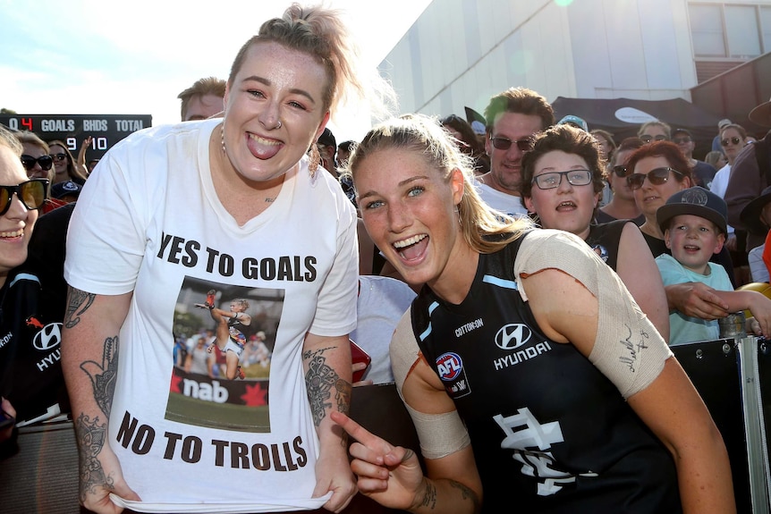 Tayla Harris celebrates with a fan wearing a 'yes to goals, no to trolls' t-shirt