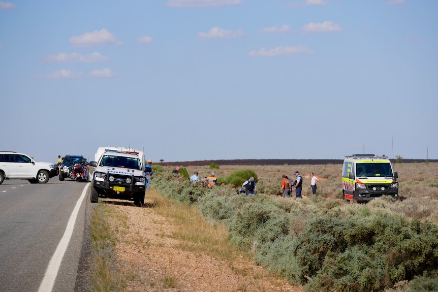 Police, Ambulance officers, friends and onlookers at the scene of a motorcycle crash on the Barrier Highway near Broken Hill. 