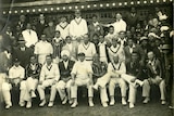 A group of men, some in blazers, some in whites, pose for a group photograph
