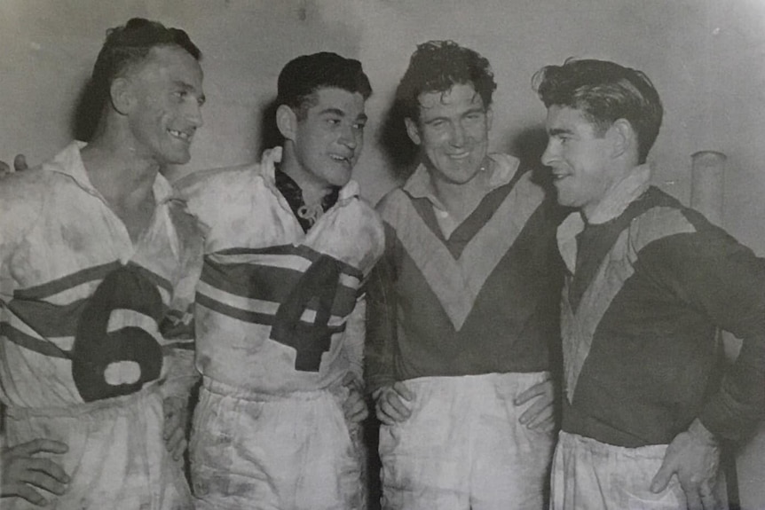 black and white photo of four men in football jerseys