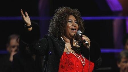 Aretha Franklin dressed in red and black singing into a microphone