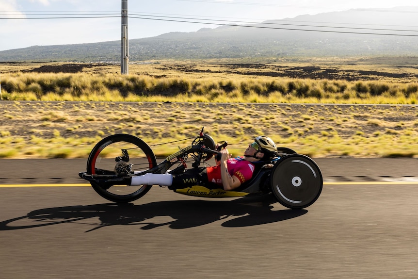 Lauren Parker lies on her back on a handcycle