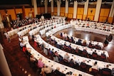 Business, union and community leaders sit in rows of tables and chairs that fill Parliament House's Great Hall.