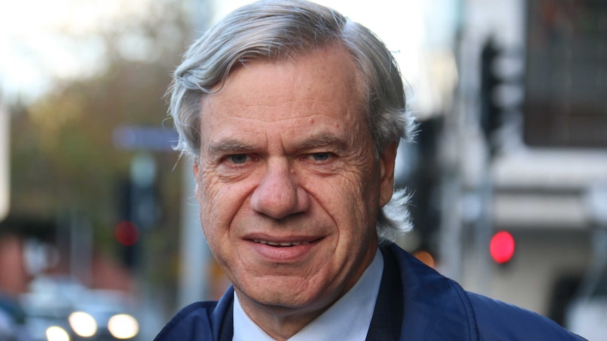 Michael Kroge, a middle-aged man with silver hair, looks towards the camera in a mid shot showing his head and shoulders.