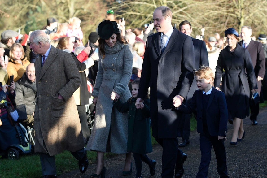 Prince Charles, Kate, Duchess of Cambridge, Prince William and their children walk along holding hands.