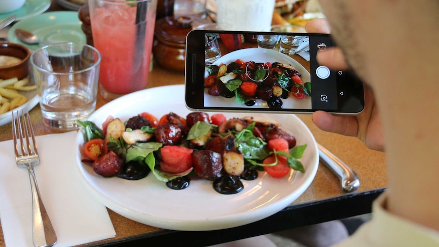 A blogger taking a photo of food in Canberra.
