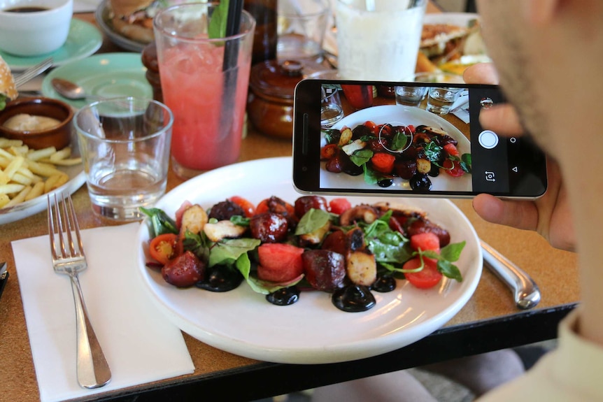 A blogger taking a photo of food in Canberra.