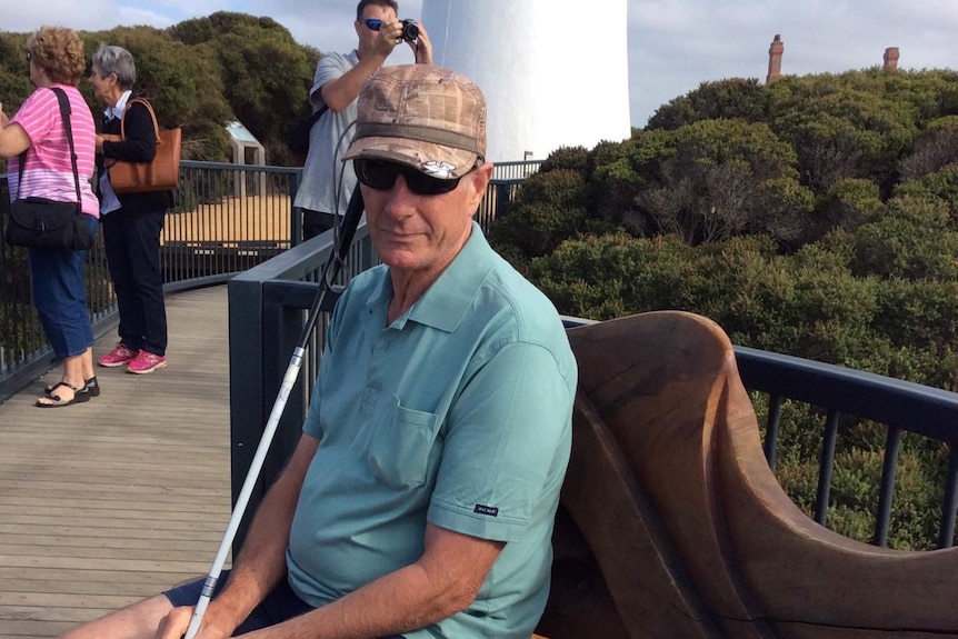 Ray Meadows sitting on a wooden bench at a tourist boardwalk