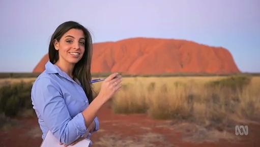 Woman stands in front of Uluru
