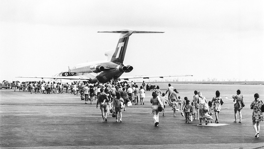Monochrome of people walking toward a plane on a runway.