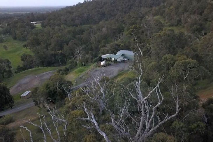 A drone shot of a remote property surrounded by dense, green bushland