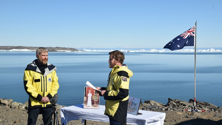 An Australian citizenship ceremony takes place at a small table on the edge of the water in Antarctica.